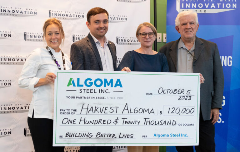 People holding a cheque that says "Harvest Algoma" for $120,000