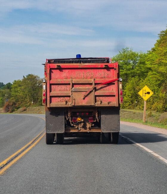 The back of a red dump truck on the highway.