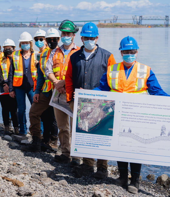 A group of people holding a board with information on it in front of a body of water
